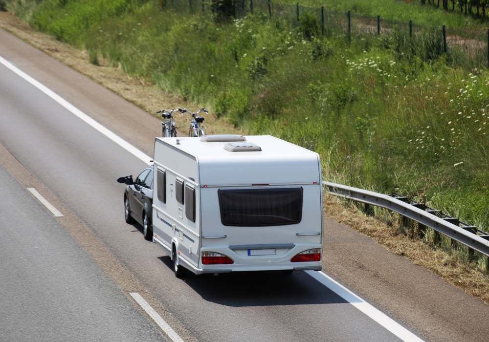 Auto che traina una roulotte su strada extraurbana